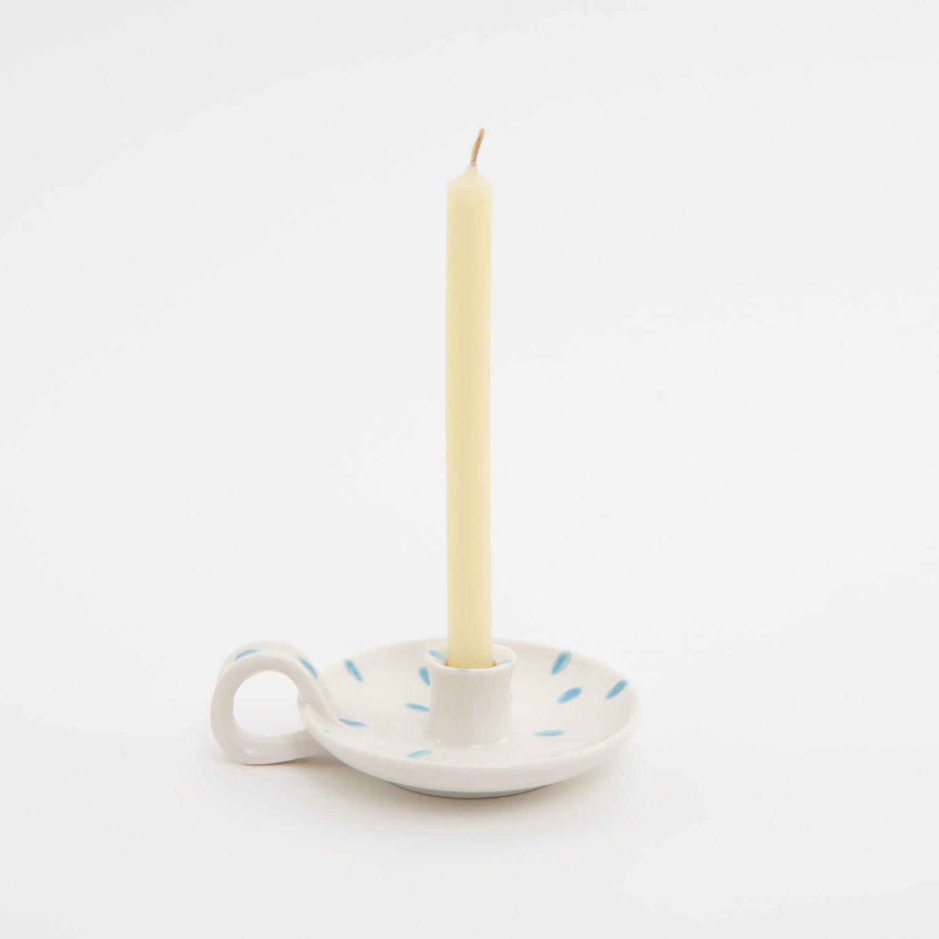 white with blue dabs ceramic candle holder with finger loop, displaying thin cream candle