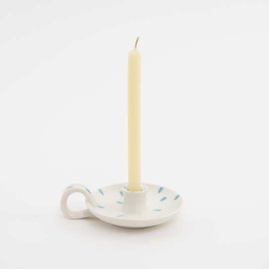 white with blue dabs ceramic candle holder with finger loop, displaying thin cream candle