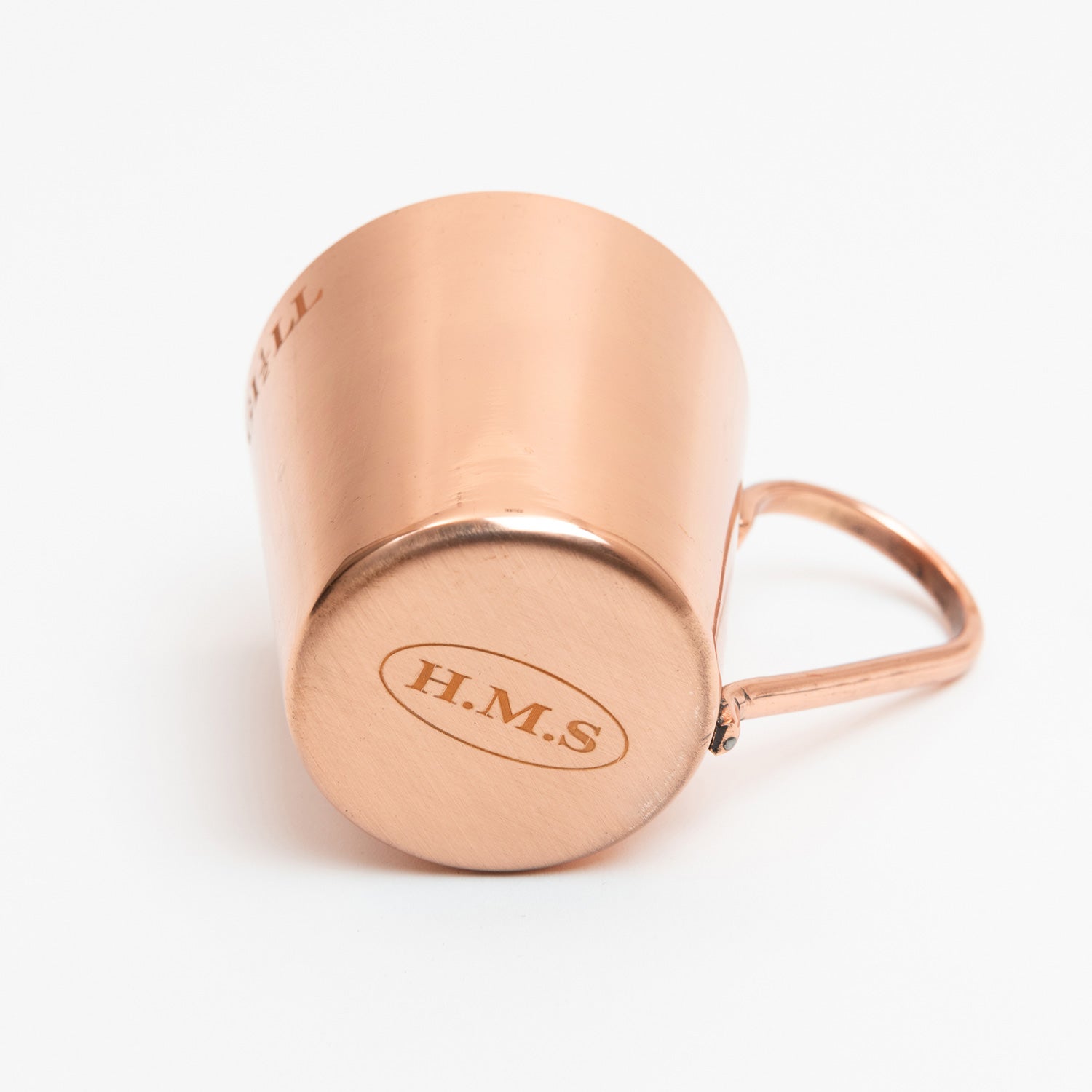 A copper-plated naval rum measure, cup with handle. Pictured on a white background.