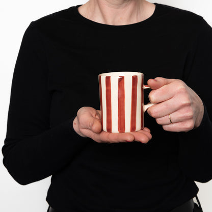 Model holding Red and white striped mug with red handle