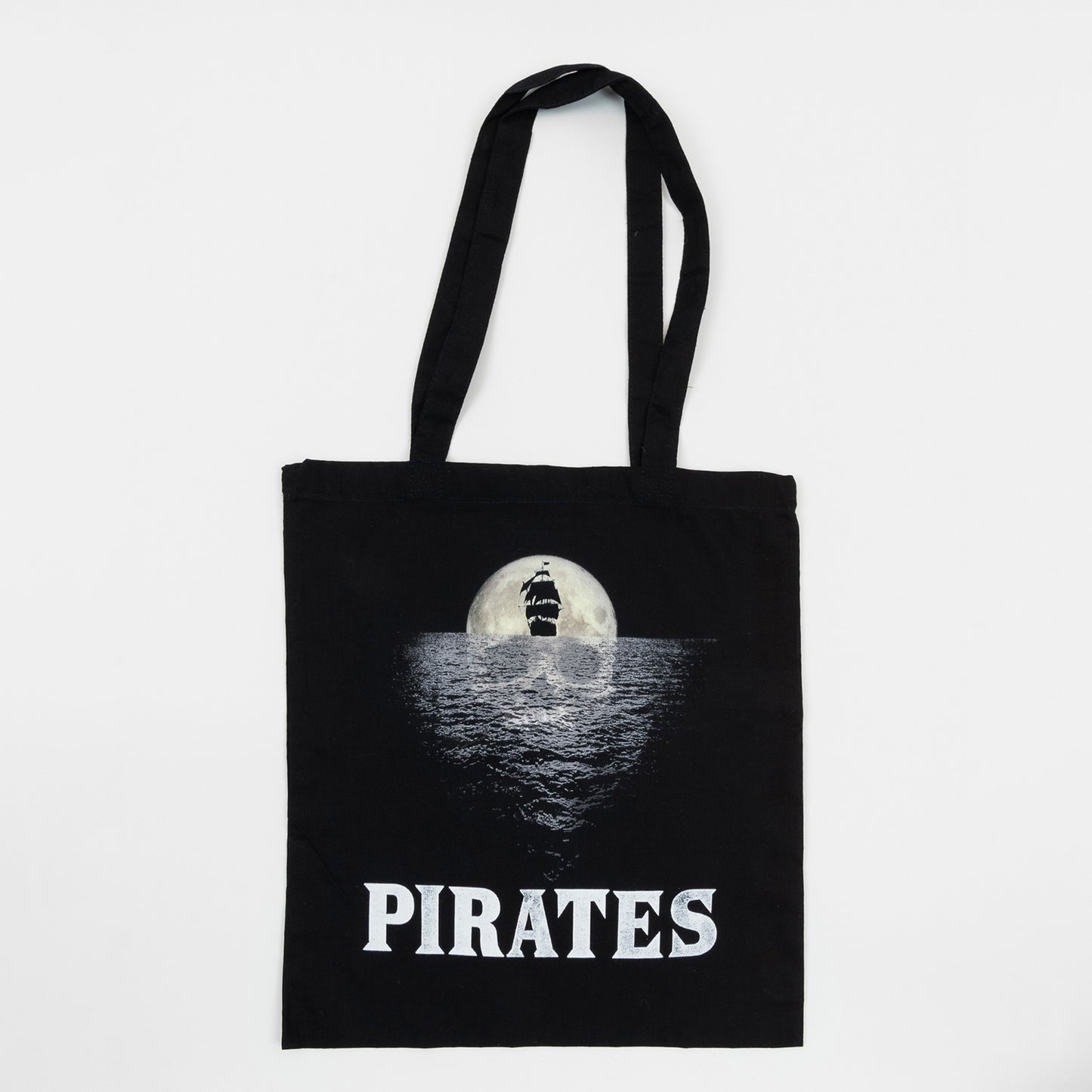 National Maritime Museum Cornwall Pirate Exhibition Tote Bag on a white background. The black tote bag features the exhibition graphic of a moon-shaped skull reflecting on the ocean behind the black shape of a ship.