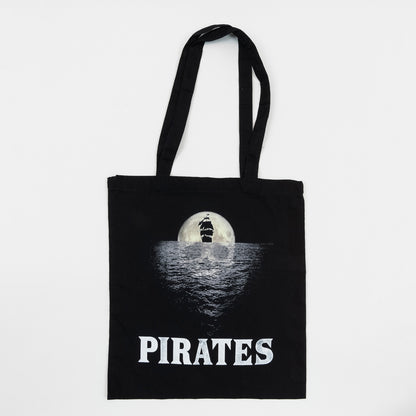 National Maritime Museum Cornwall Pirate Exhibition Tote Bag on a white background. The black tote bag features the exhibition graphic of a moon-shaped skull reflecting on the ocean behind the black shape of a ship.