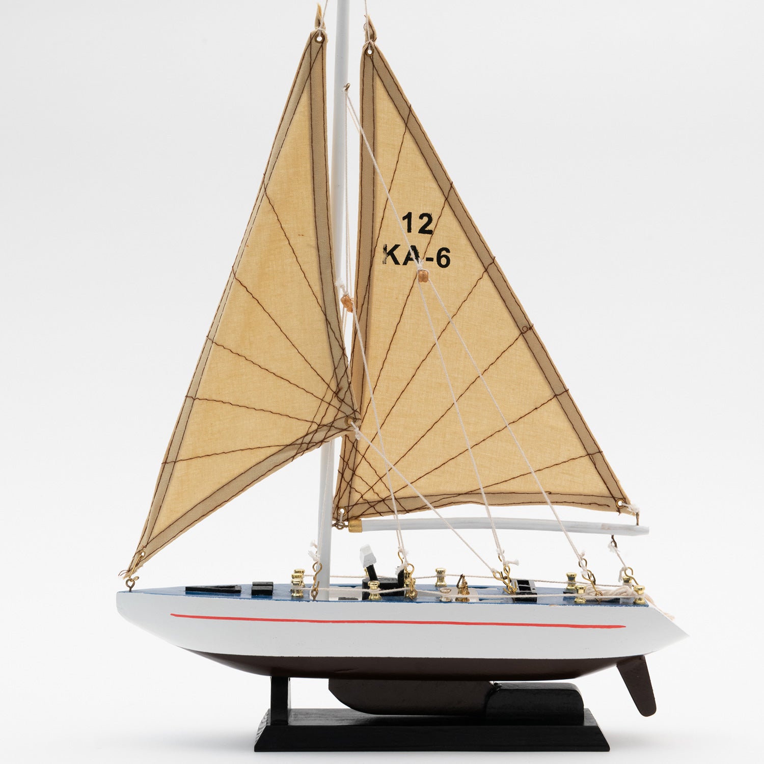 View of the side of the model racing yacht with a black and white hull and a tan sails.