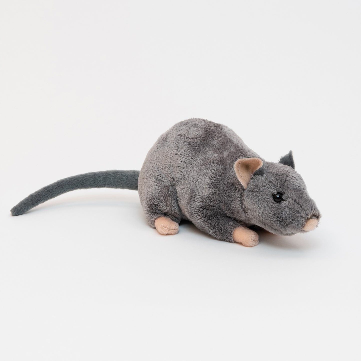 Side view of a grey fluffy rat with pink ears, nose and paws and a long grey tail.