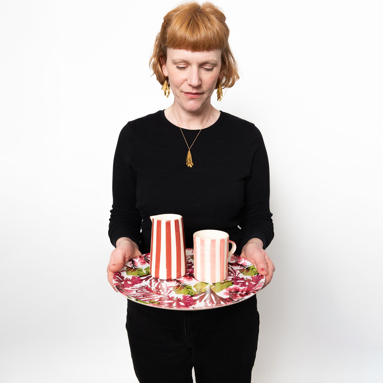 Model holding a tray demonstrating the size of the Pink and white wide striped mug with pink handle