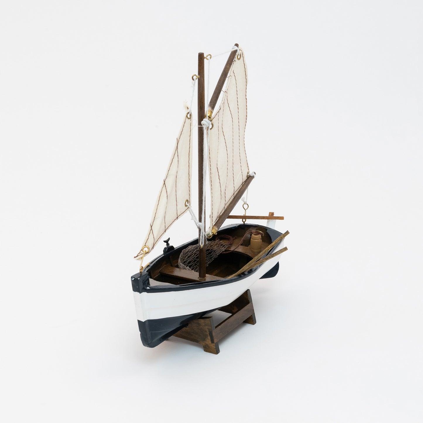 Front view of the model sailing boat with a navy blue and white hull and cream sails.