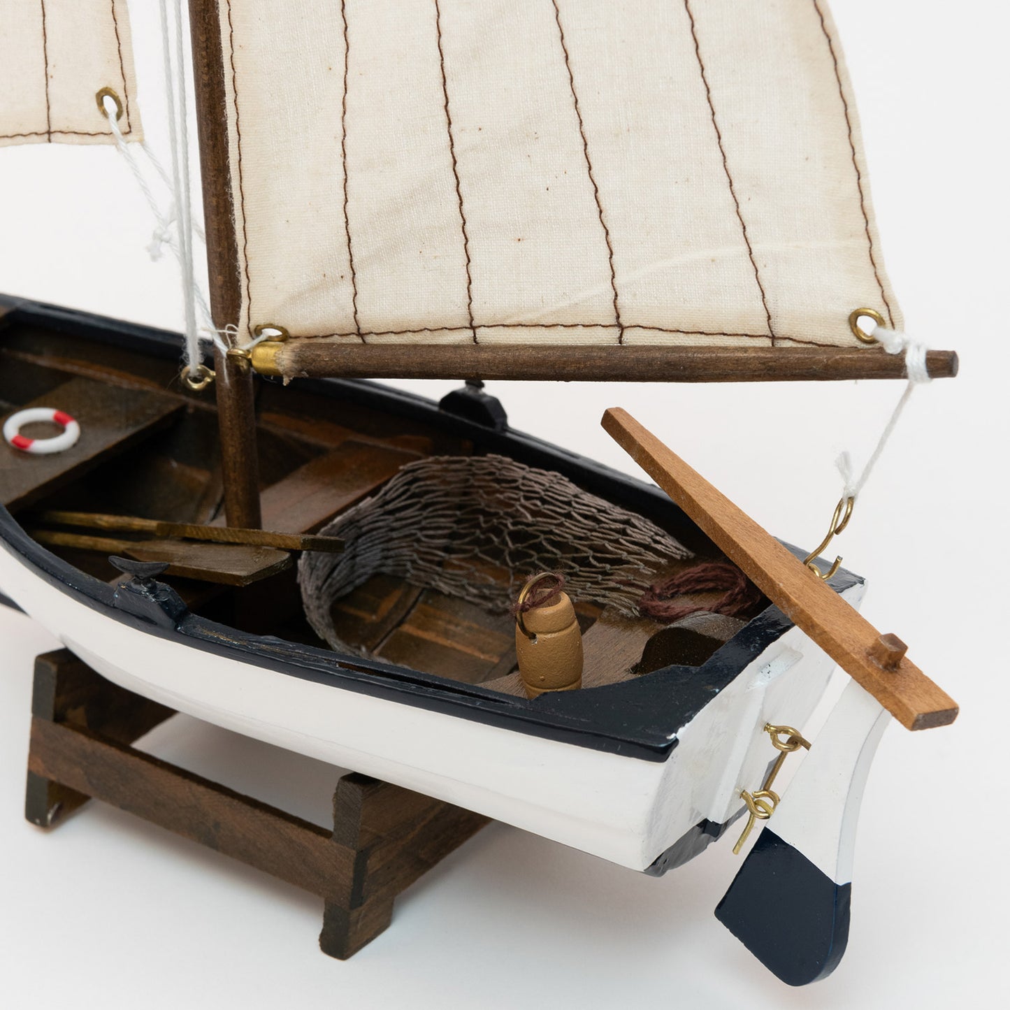 Close-up of the model sailing boat including the rudder and netting on display.