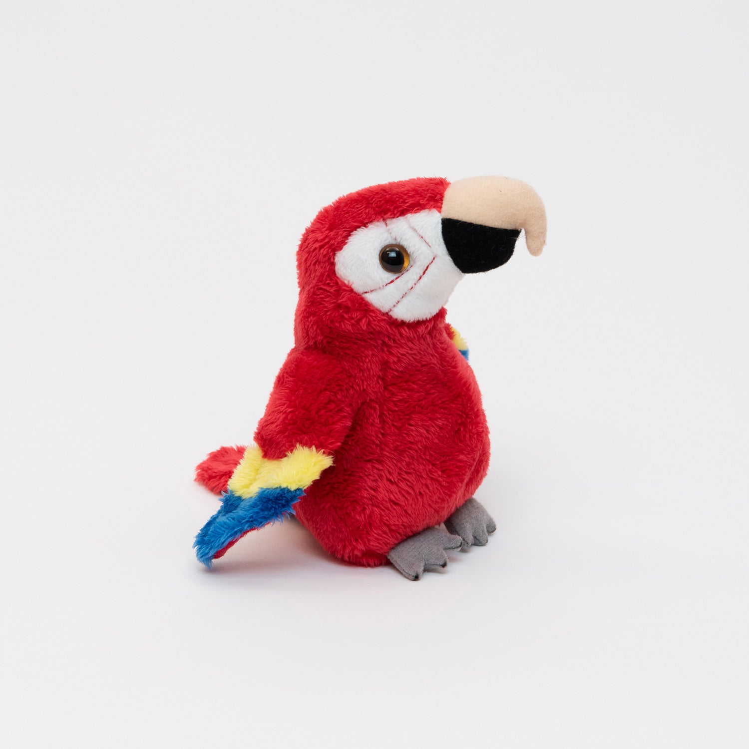 A plush scarlet macaw parrot on a white background.