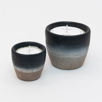 St Eval Sea Salt Small  & Large Coastal Candle in heavy stoneware pot. Natural stone clay base fading into a deep navy blue ring at top of pot. St Eval card circle protector on top of candle with wick standing tall.