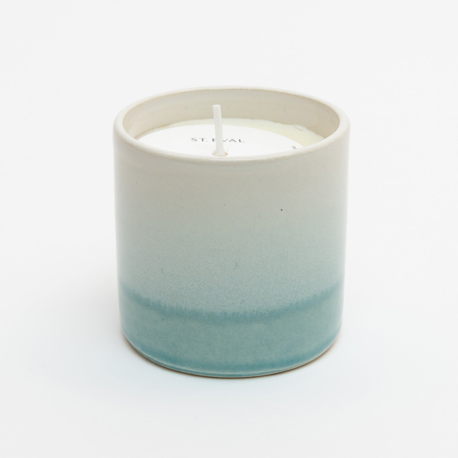 St Eval Sea & Shore Salt candle pot. Stoneware ceramic pot. Cream top fading to pale blue ring at base. St Eval card circle protector on top of candle with wick standing tall.