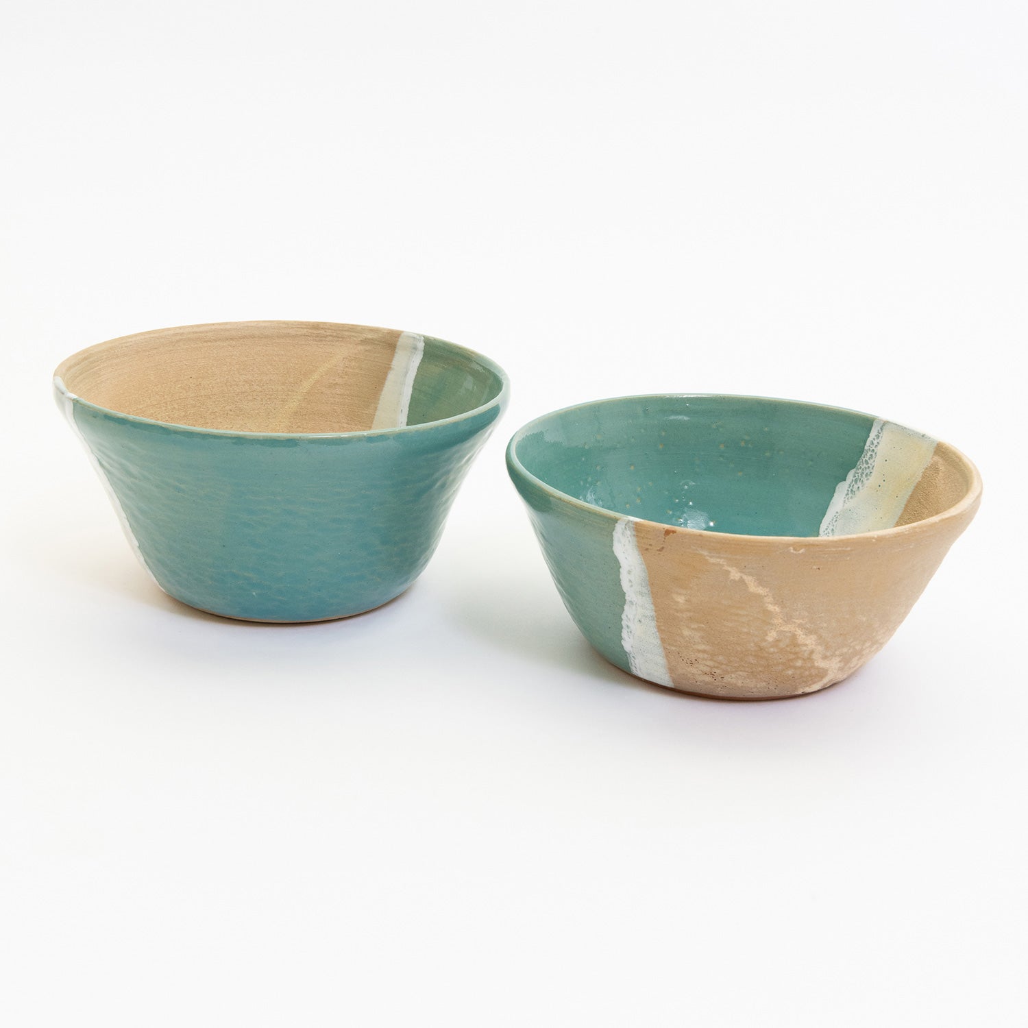 Two bowls pictured on a white background. Each bowl has an ocean shoreline design, with the sea, a wave, and the sand across it.