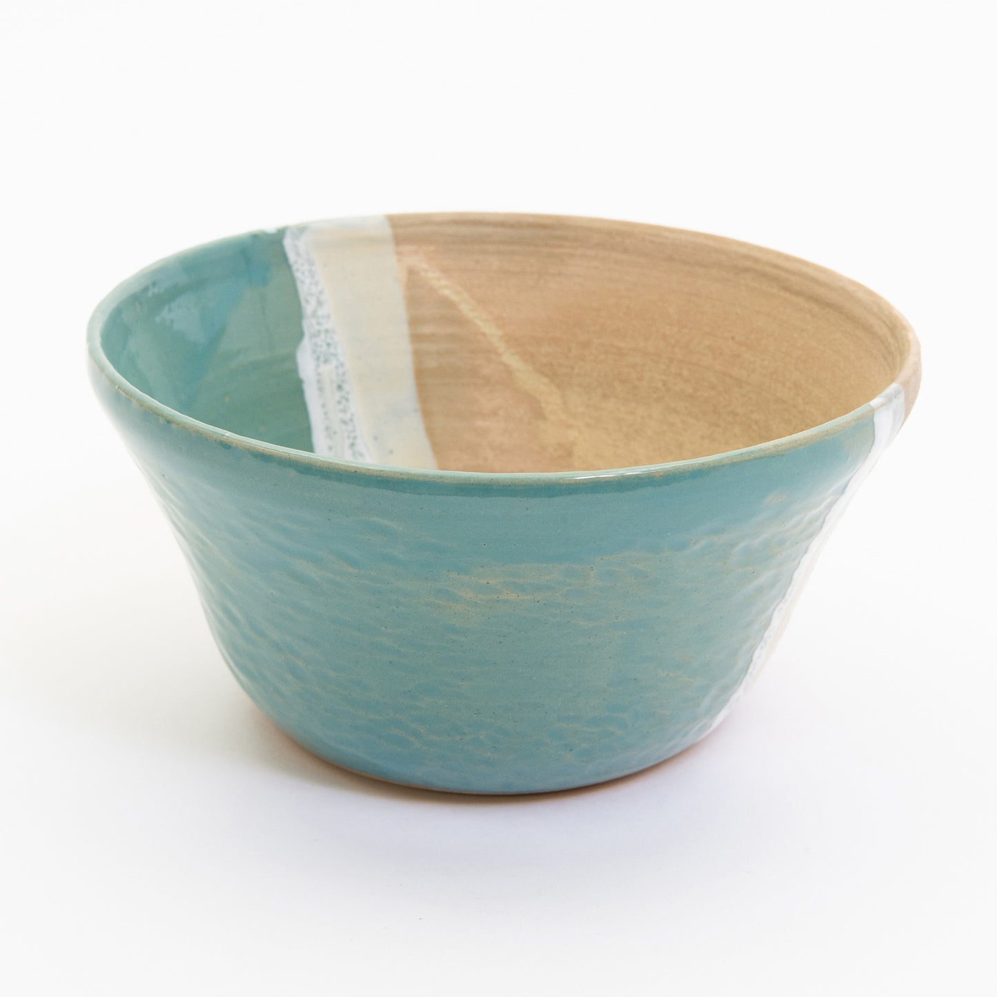A bowl pictured on a white background. The bowl has an ocean shoreline design, with the sea, a wave, and the sand across it.