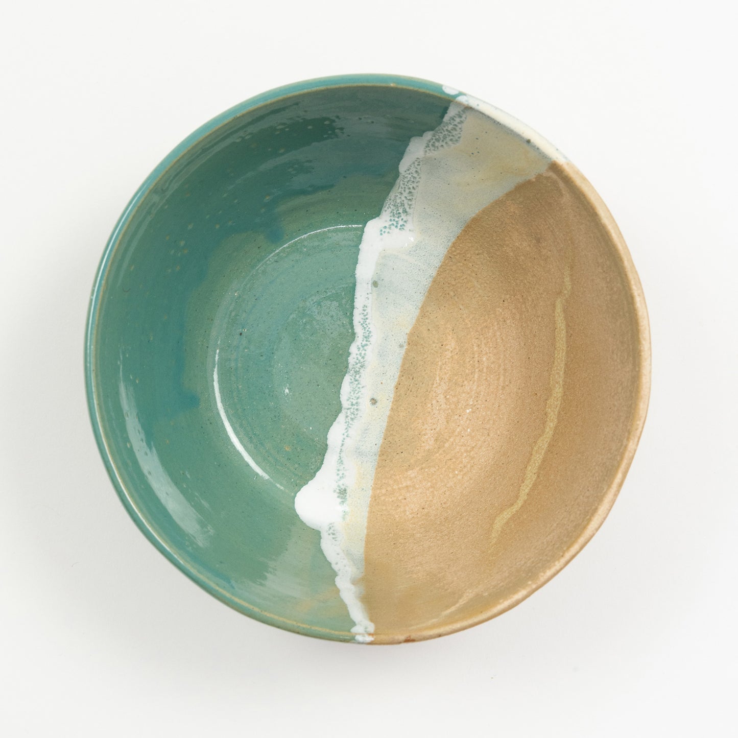 A bowl pictured on a white background. The bowl has an ocean shoreline design, with the sea, a wave, and the sand across it.