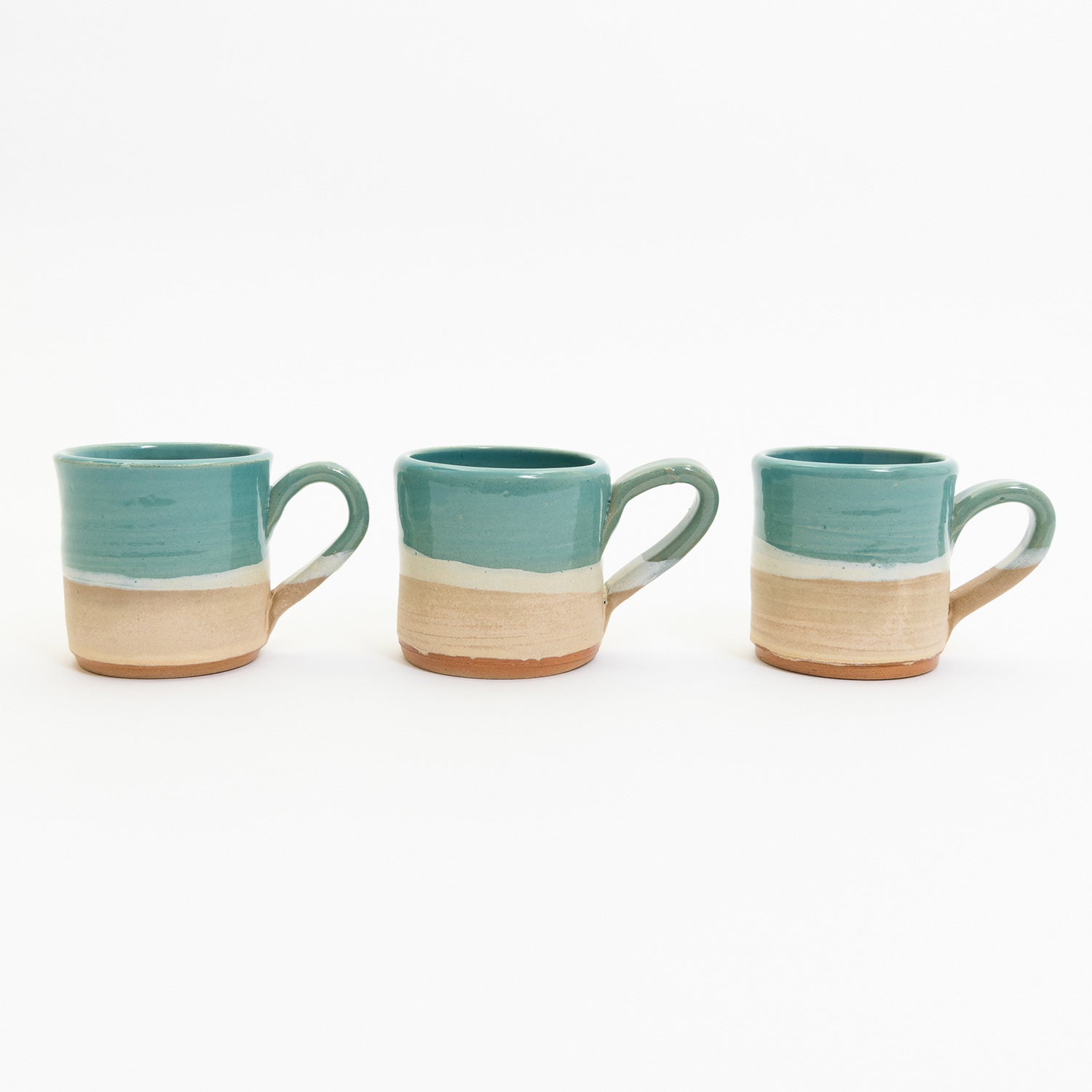 Espresso cups pictured on a white background. The cup has an ocean design, with the sea, a wave, and the sand across it.