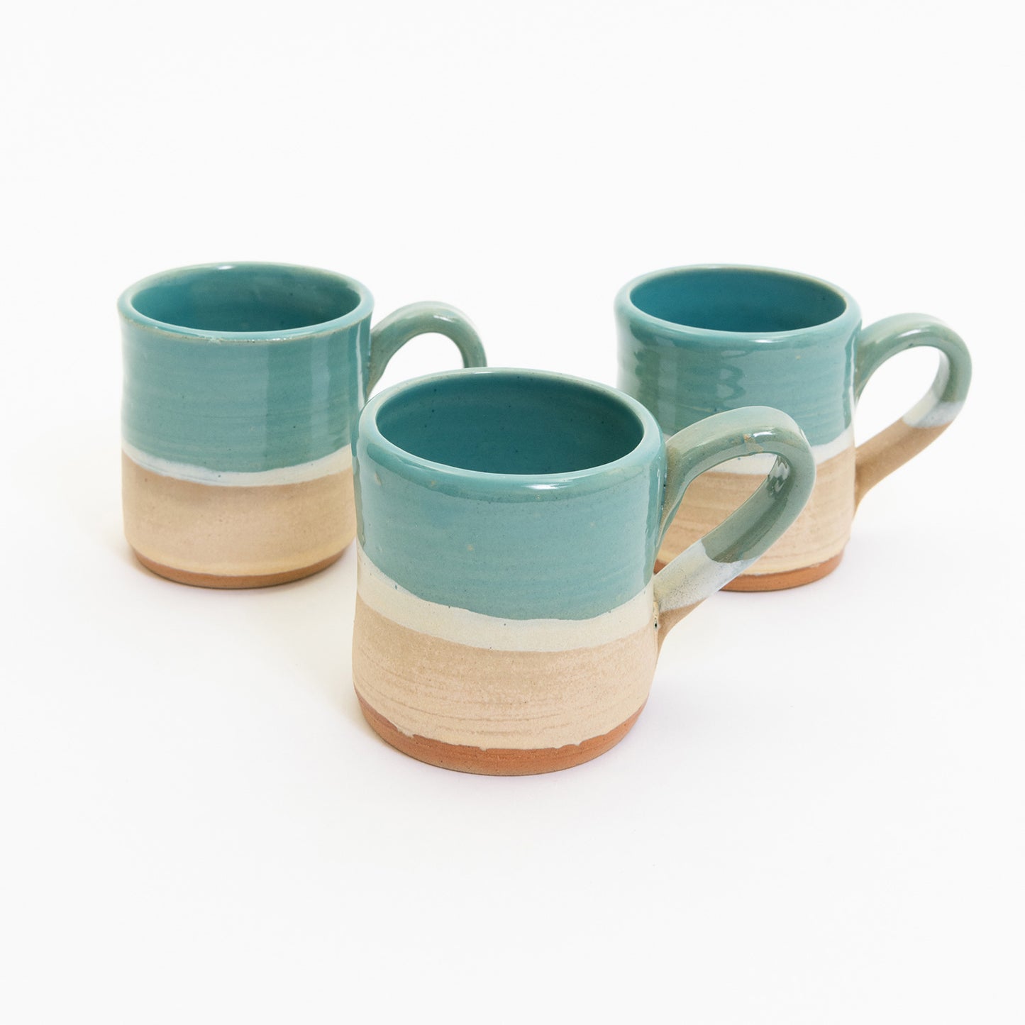 Espresso cups pictured on a white background. The cup has an ocean design, with the sea, a wave, and the sand across it.