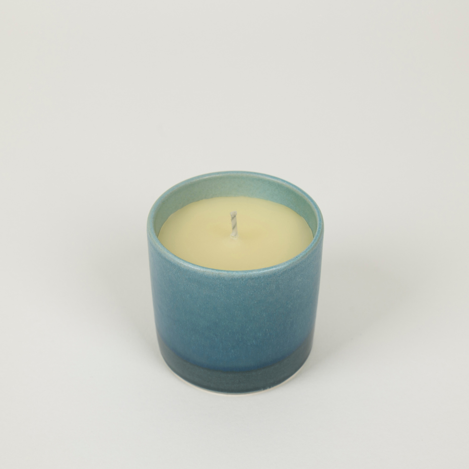 Candle in a blue ceramic holder on a white background