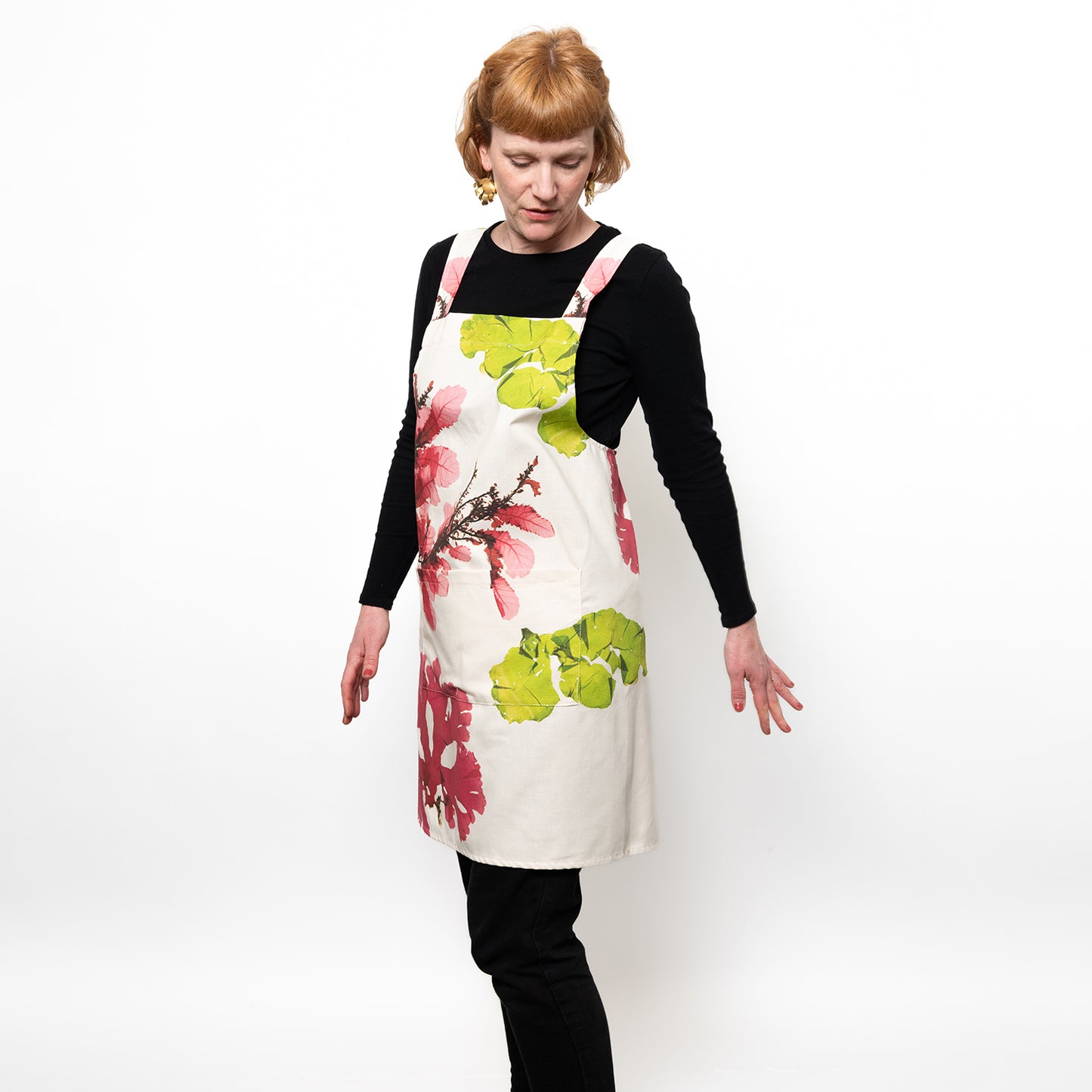 Model wearing white apron with large seaweed pressings in pink and green