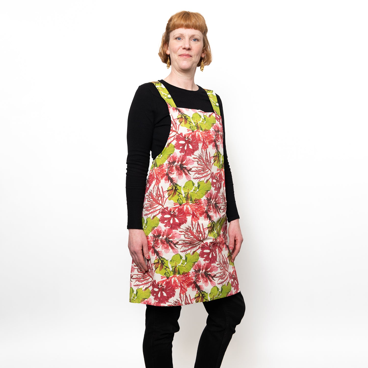 Model wearing a cross back apron in green and pink coloured seaweed design