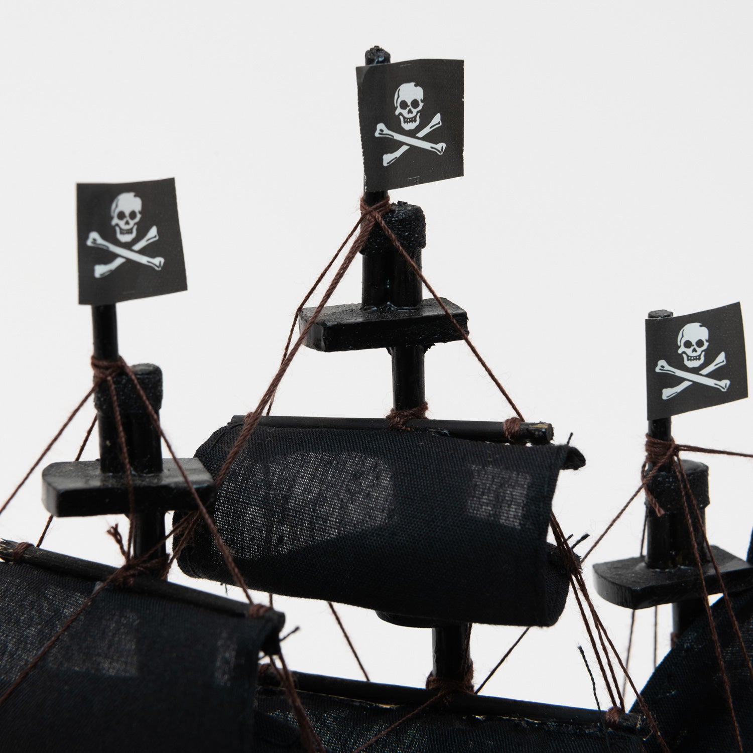 A close-up of three of the jolly roger flags on the pirate model ship.