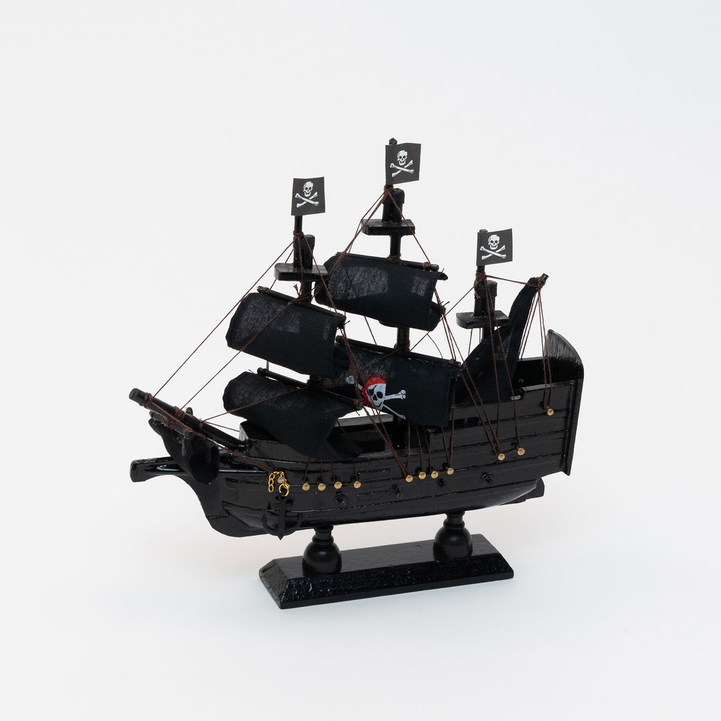Side view of the black model pirate ship with a jolly roger on four of the black sails.