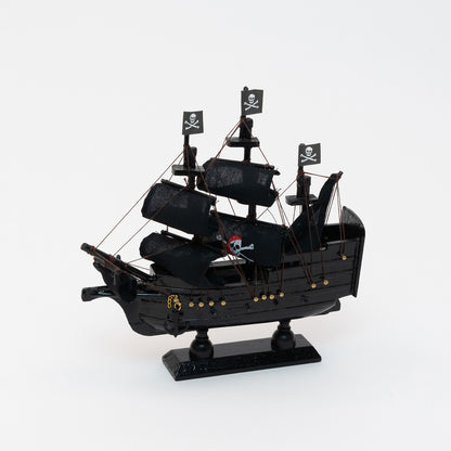 Side view of the black model pirate ship with a jolly roger on four of the black sails.