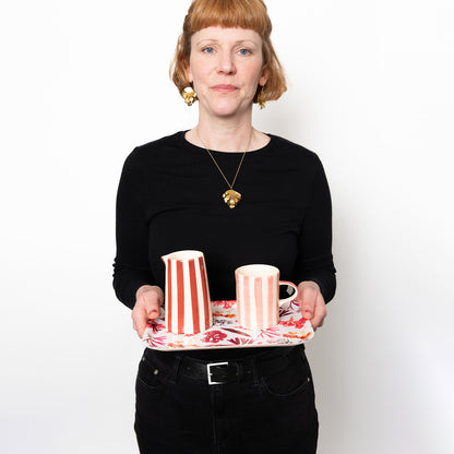 Model holding rectangular tray featuring seaweed pressings in pinks, reds and  maroons