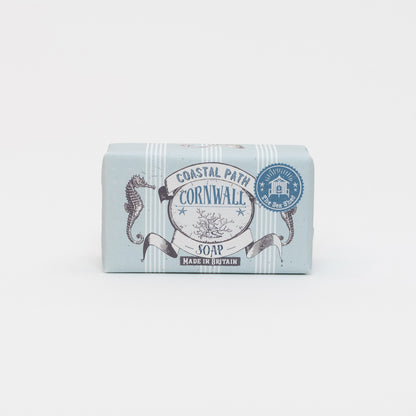 A photo of packaged coastal path soap on a white background. The soap has blue and white packaging with illustrations of seahorses and seaweed. 