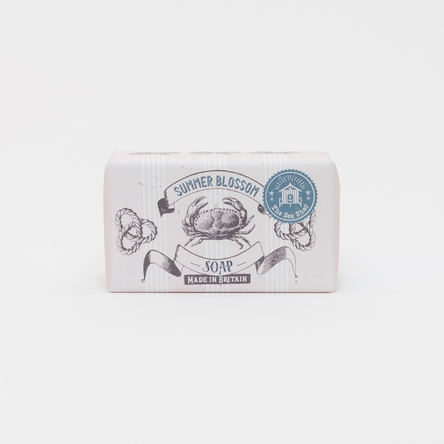 A photo of packaged summer blossom soap on a white background. The soap has white packaging with illustrations of a crap and rope.