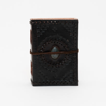 A view of the cover of a dark brown leather bound journal with a grey stone detail in the centre.