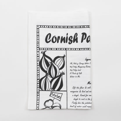 Folded black and white Cornish pasty recipe tea towel against a white background.