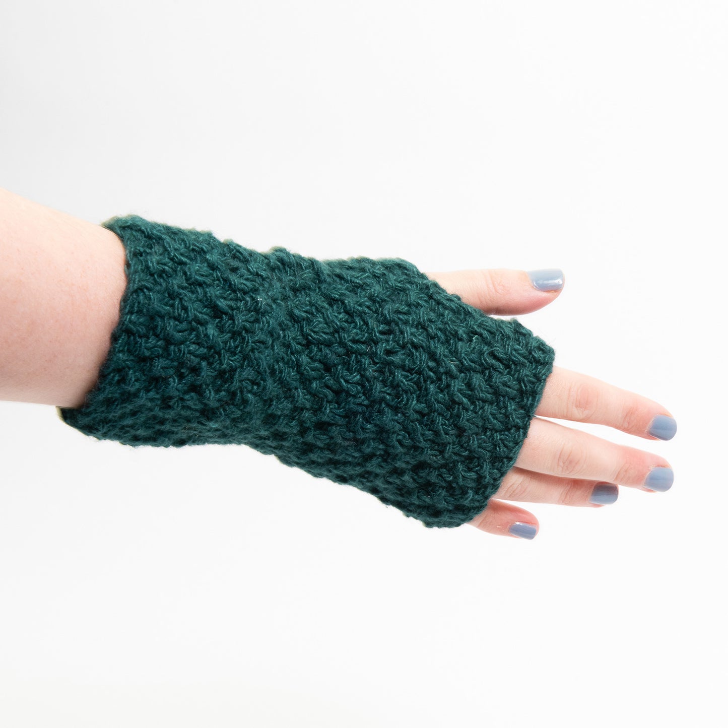 A teal green wristwarmer modelled on a hand and pictured on a white background.