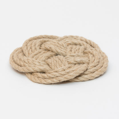 Light brown knotted rope trivet in a circular shape.
