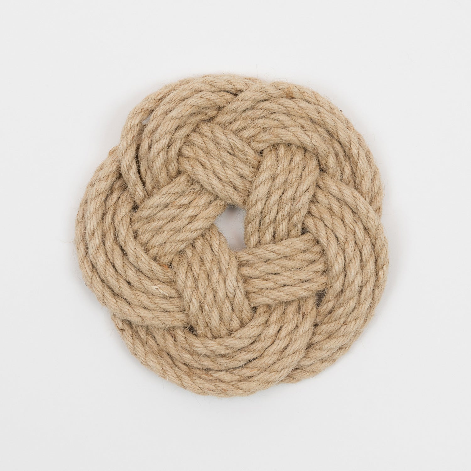 Top down view of a light brown knotted rope trivet in a circular shape.