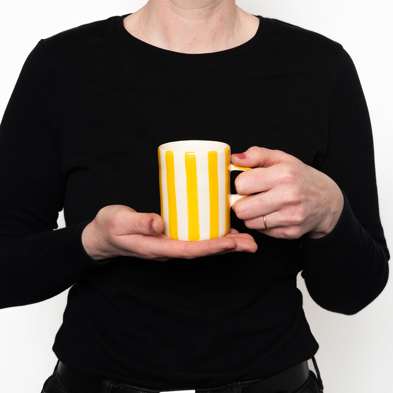 model demonstrating size of Yellow and white striped mug with yellow handle 