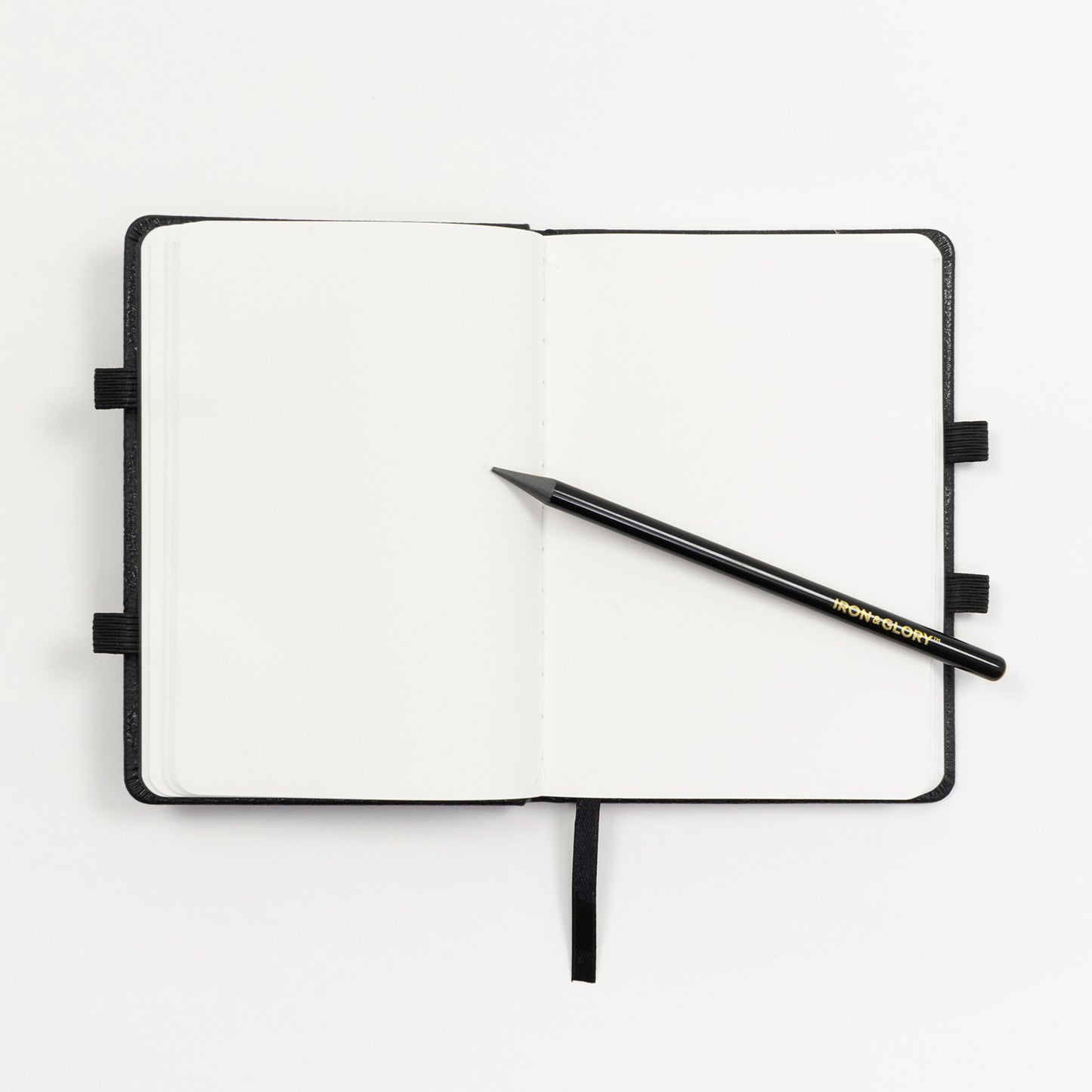 An open notebook with blank pages. A graphite pencil rests on the open page. Pictured on a white background.