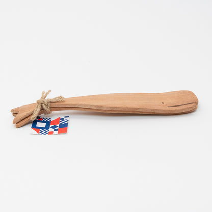Side and top view of the wooden salad servers shaped like a whale. There is brown string securing the servers together with a label.