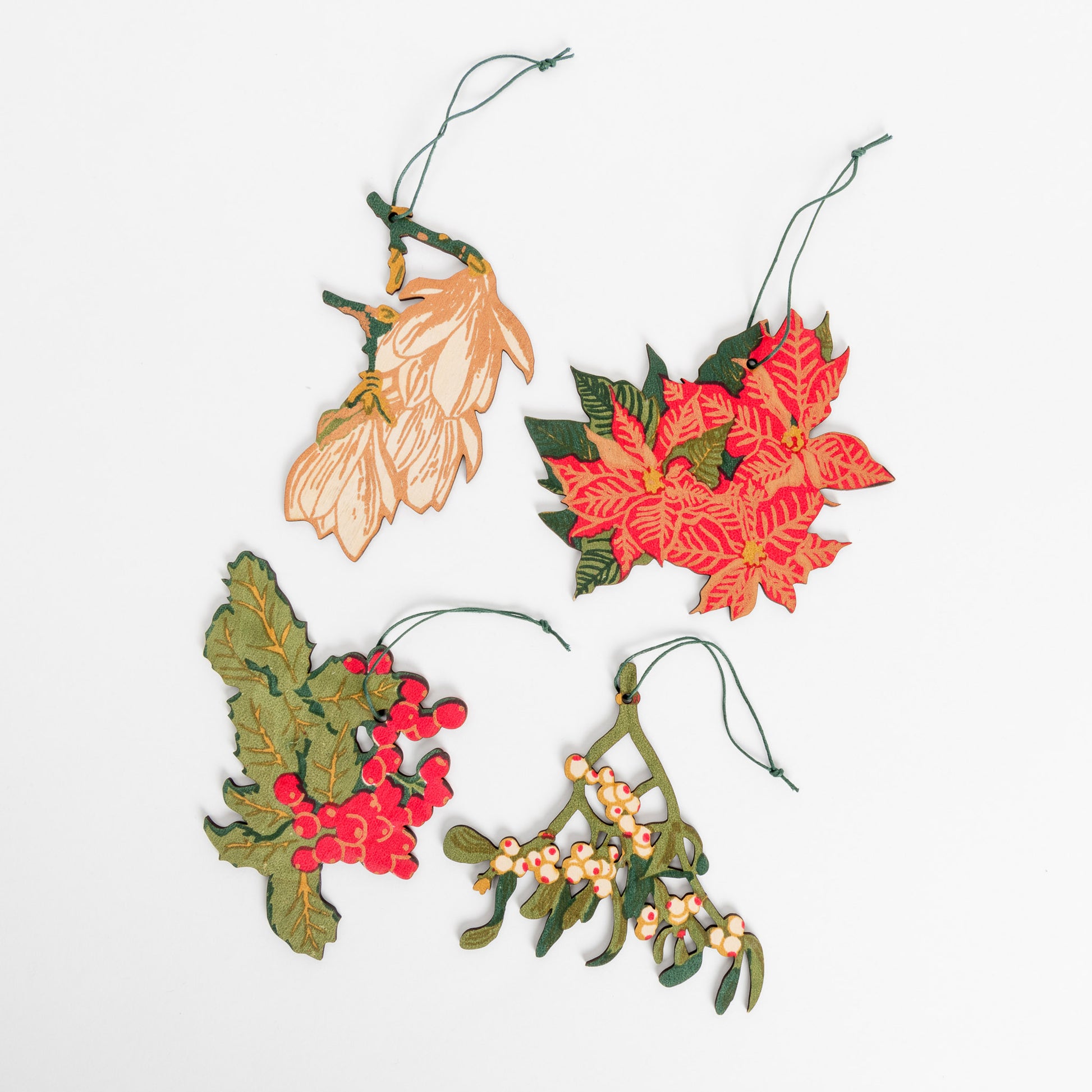 Showing 4 wooden decorations of mistletoe, poinsettia, magnolia and holly in red and green.